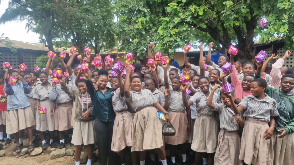 Students displaying sanitary pads received during an Emerald Atibire Foundation menstrual health outreach.